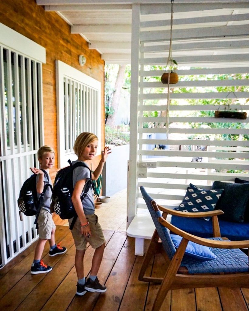 boys waving goodbye going to school with a healthy snack in their lunchbox