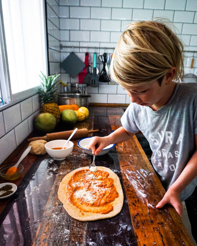 spreading grated cheese on rolled out dough