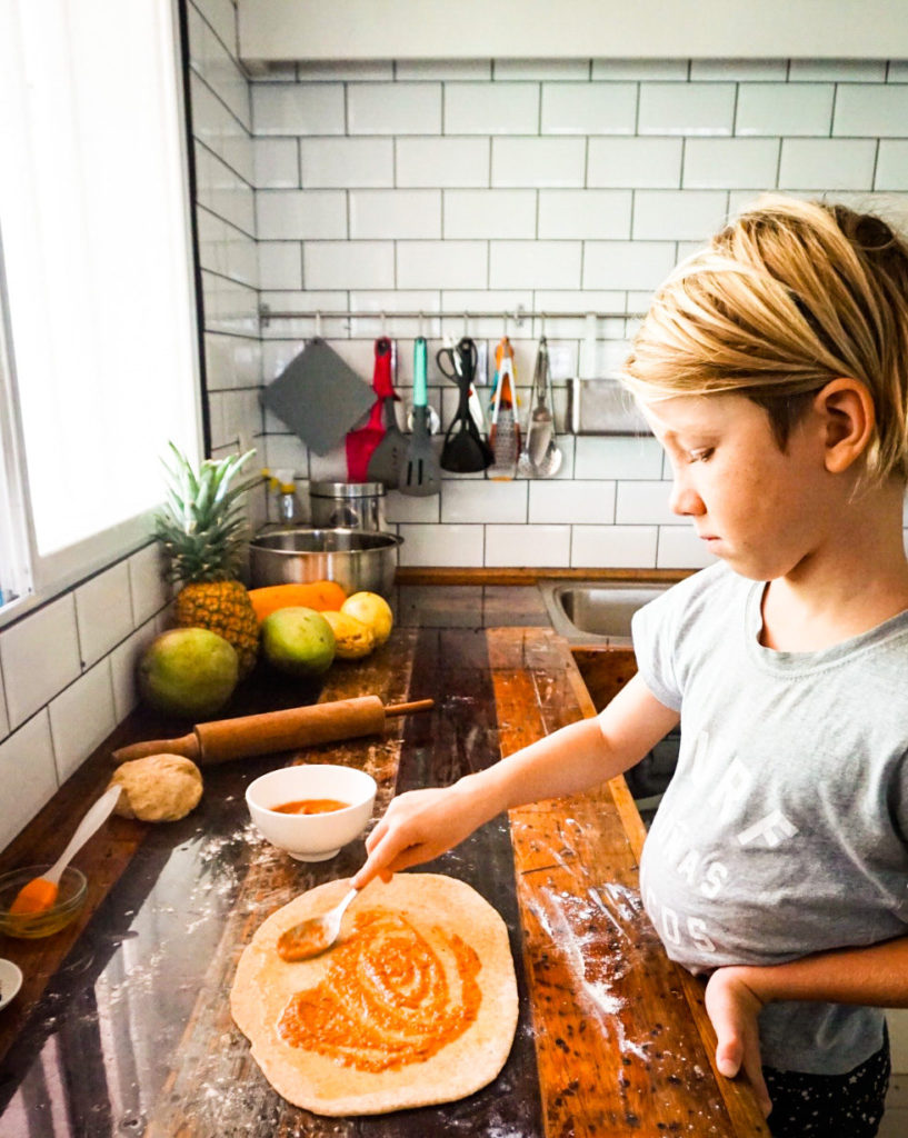 spreading tomato sauce on dough