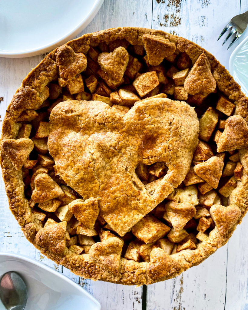 apple pie on table with plates and forks