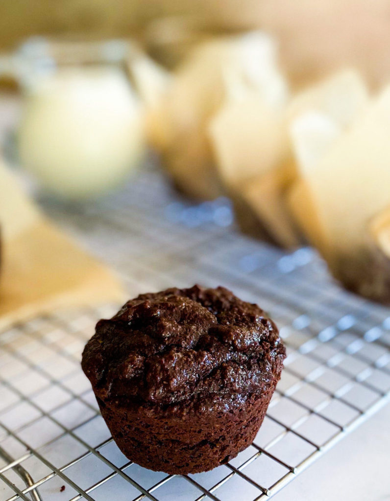 Brownie muffins on a cooling rack with many muffins in its wrapper in the background