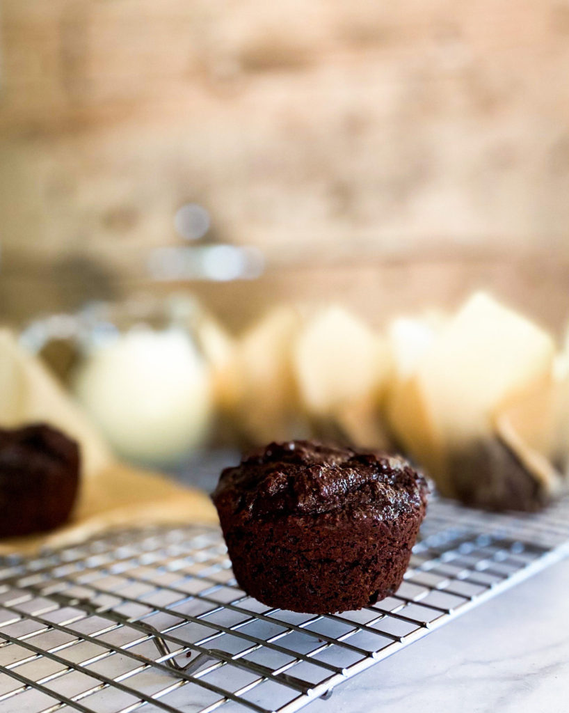 Brownie muffins on a cooling rack with many muffins in its wrapper in the background