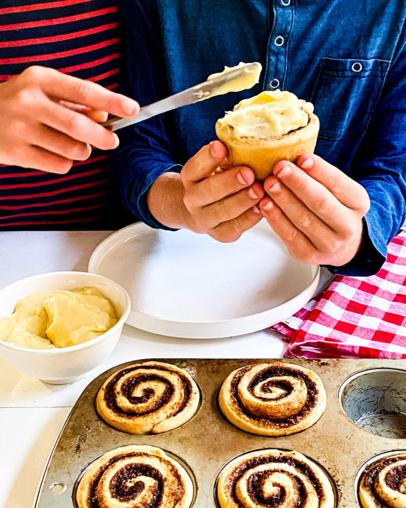 Kids spreading frosting on their cinnamon roll