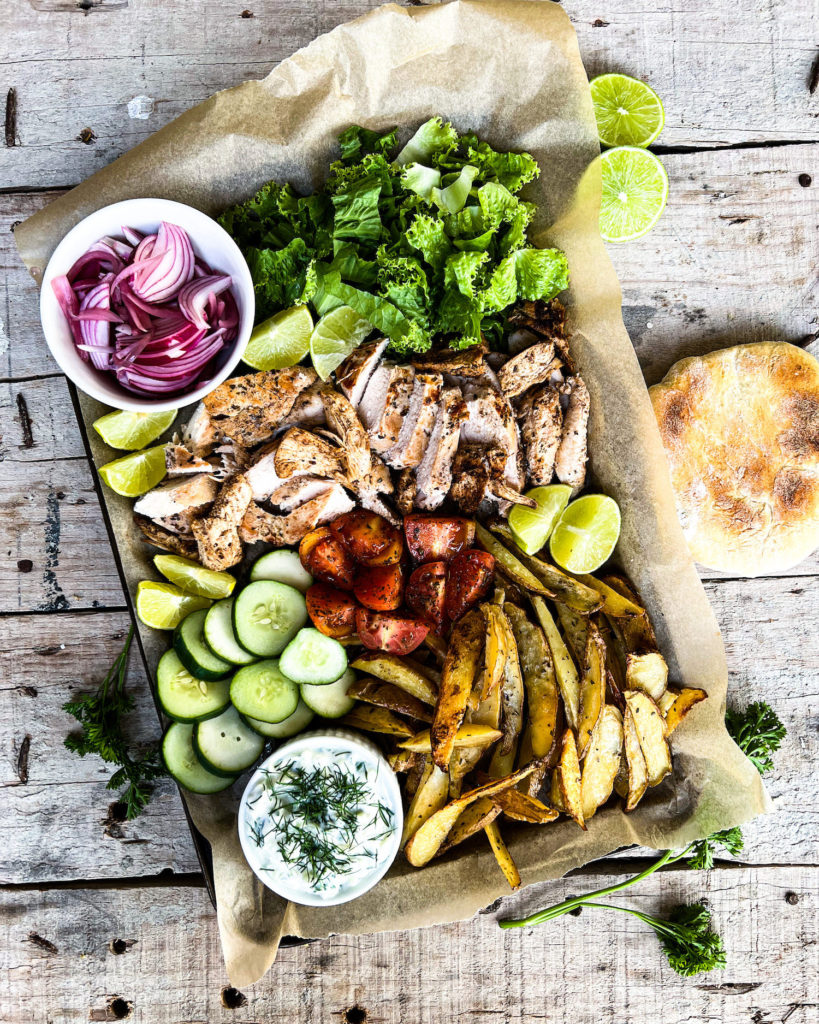 Lemon marinated chicken pitas with oven baked fries and tzatziki sauce on a bake tray