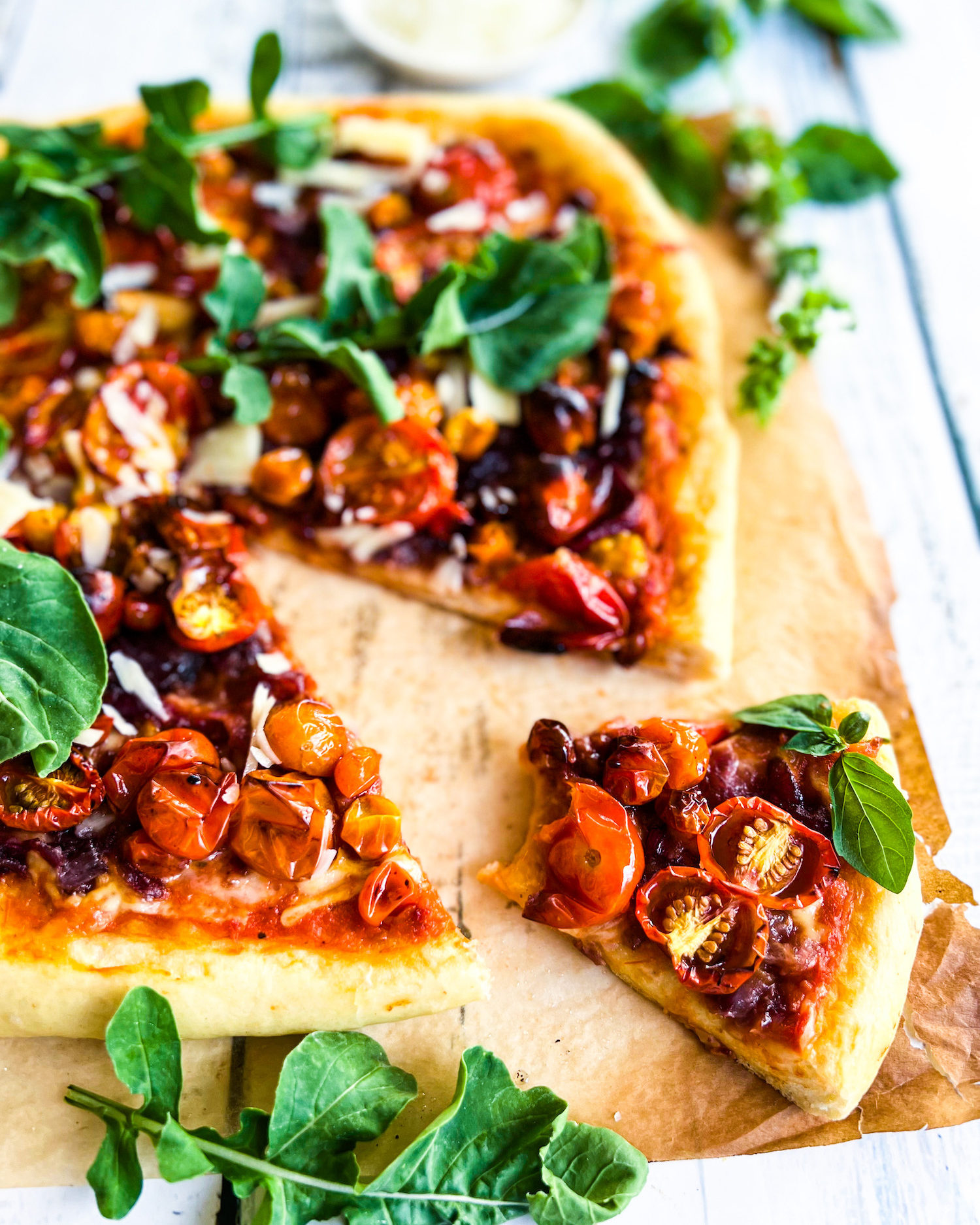 a slice of roasted cherry tomato pizza with onion spread topped with arugula and parmesan 1