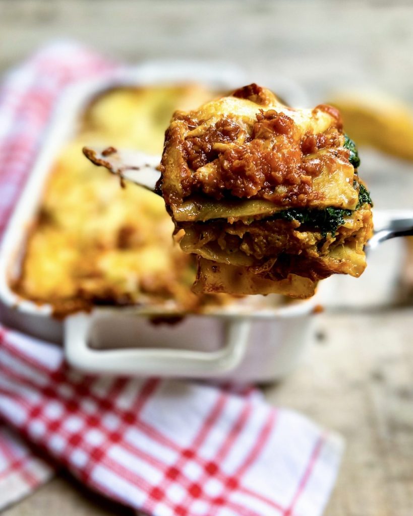 a piece of pumpkin lasagna with the lasagna dish in the background