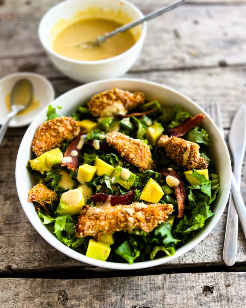 chicken finger salad in a bowl with dressing on the side