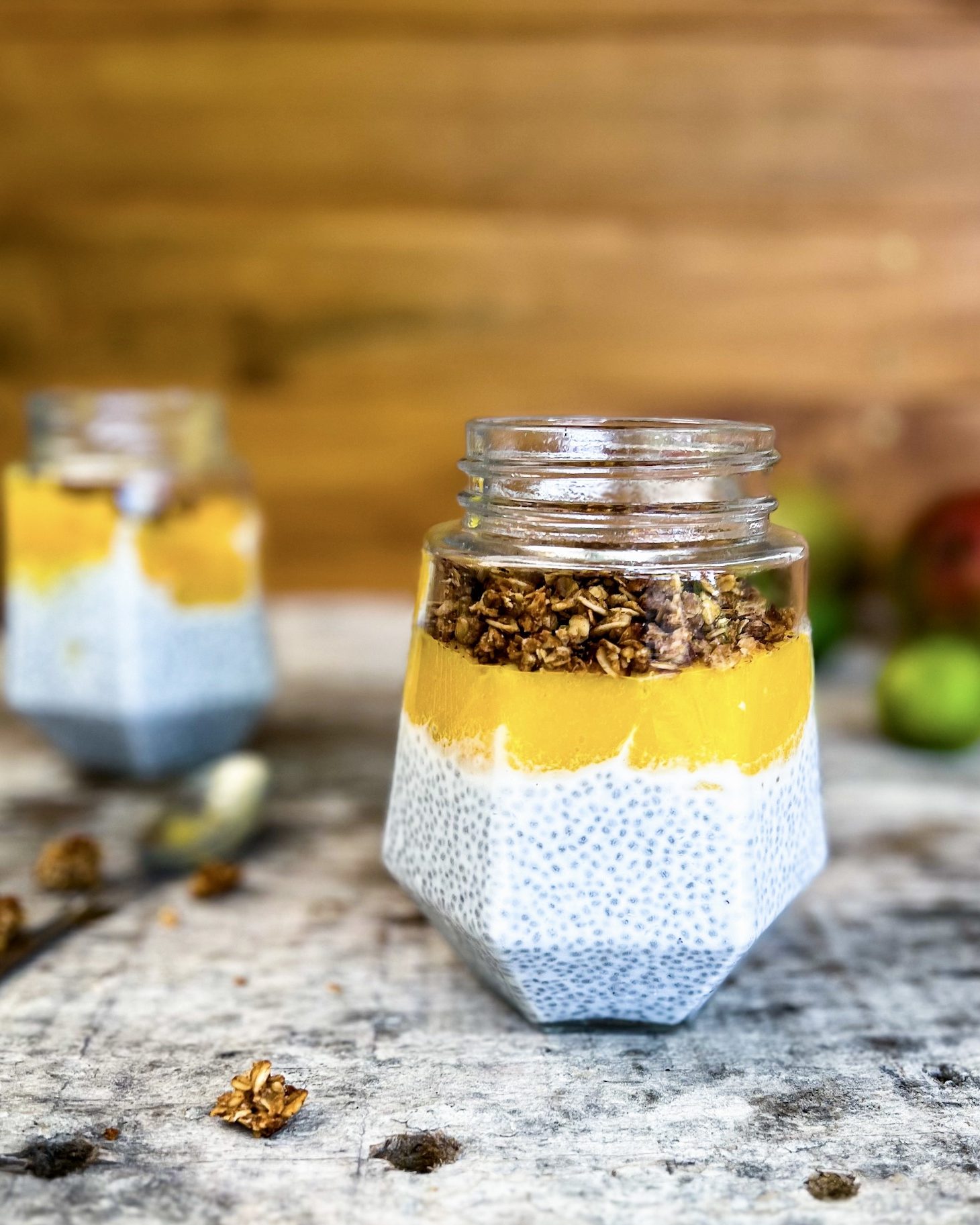 coconut chia pudding in a jar with mango puree and topped with homemade granola