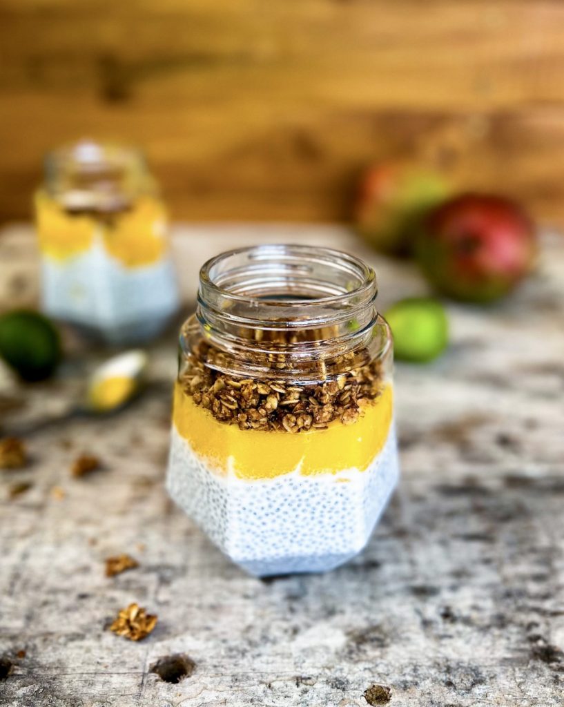 coconut chia pudding in a jar with mango puree and topped with homemade granola