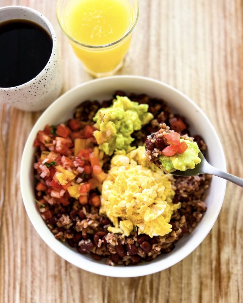 A bite of gallo pinto with scrambled eggs, pico de gallo and avocado