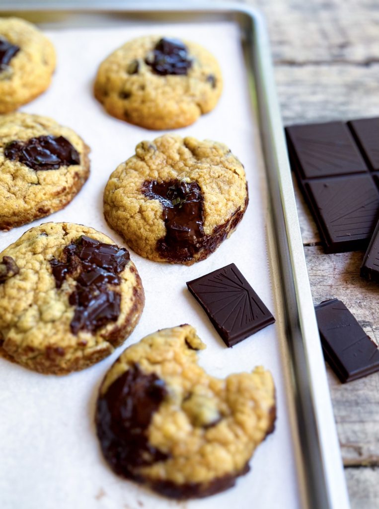 A tray of cakey chocolate chip cookies and chunks of chocolate on the side