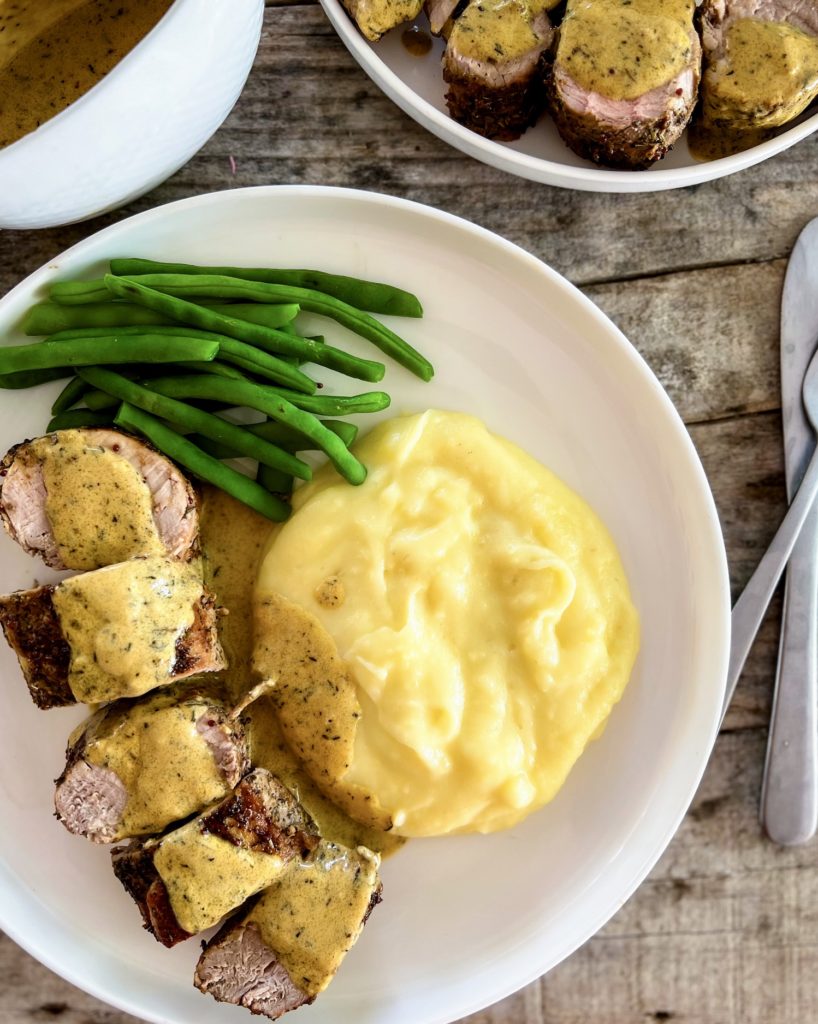 pork tenderloin medallions on a plate with mashed potatoes and green beans