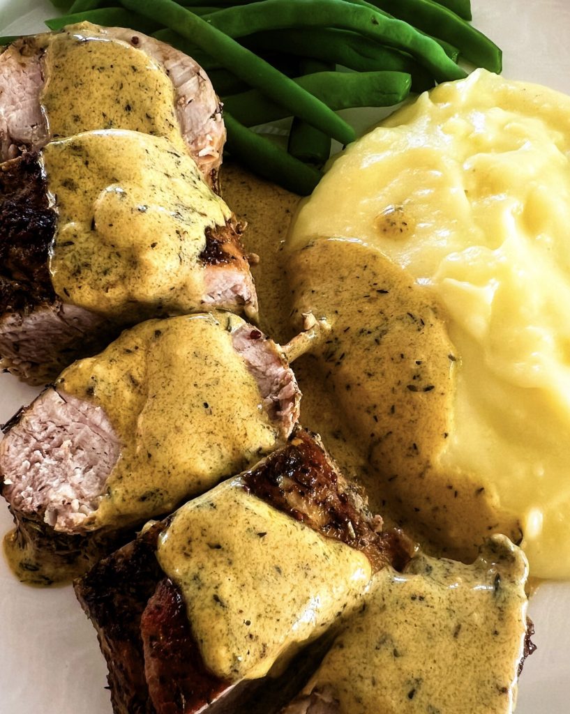 pork tenderloin medallions on a plate with mashed potatoes and green beans close up